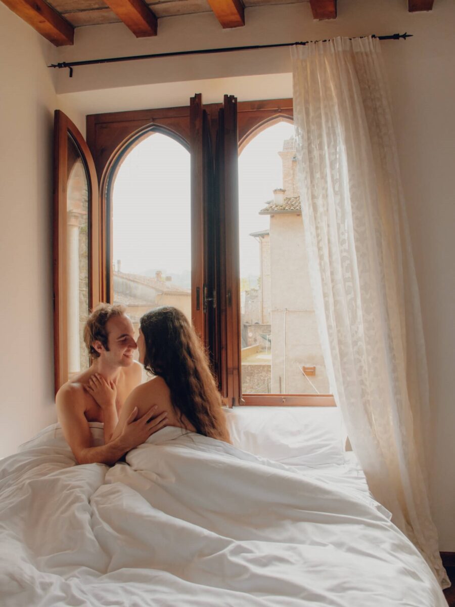 una coppia di innamorati che si abbraccia in un letto matrimoniale con vista